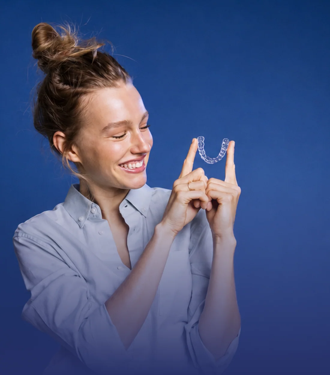 Mulher sorrindo segurando um alinhador invisível na Studio do Sorriso